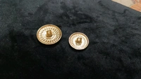 12 round metal buttons in gold and black. They have an embossed design and a shank on the back. Six buttons are larger, and six are smaller. These buttons can be used for coats, blazers, suits, sherwanis, and other Indian dresses. 