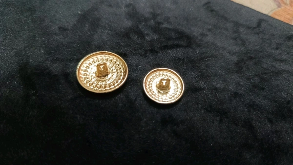 12 round metal buttons in gold and black. They have an embossed design and a shank on the back. Six buttons are larger, and six are smaller. These buttons can be used for coats, blazers, suits, sherwanis, and other Indian dresses. 